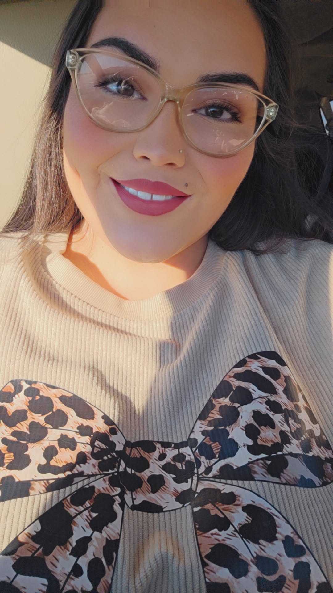 Woman wearing glasses with a beige sweater and leopard print bow